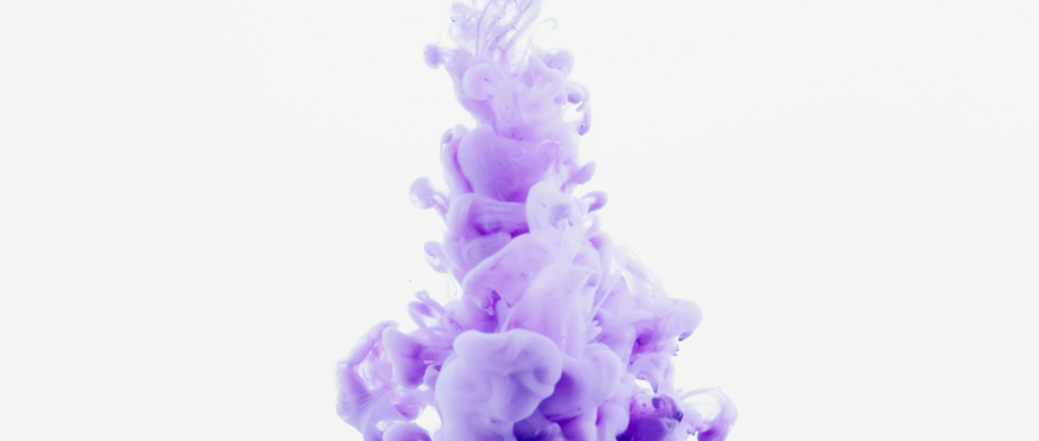 Dynamic high-speed photo of purple ink swirling in water, creating a vibrant abstract design.